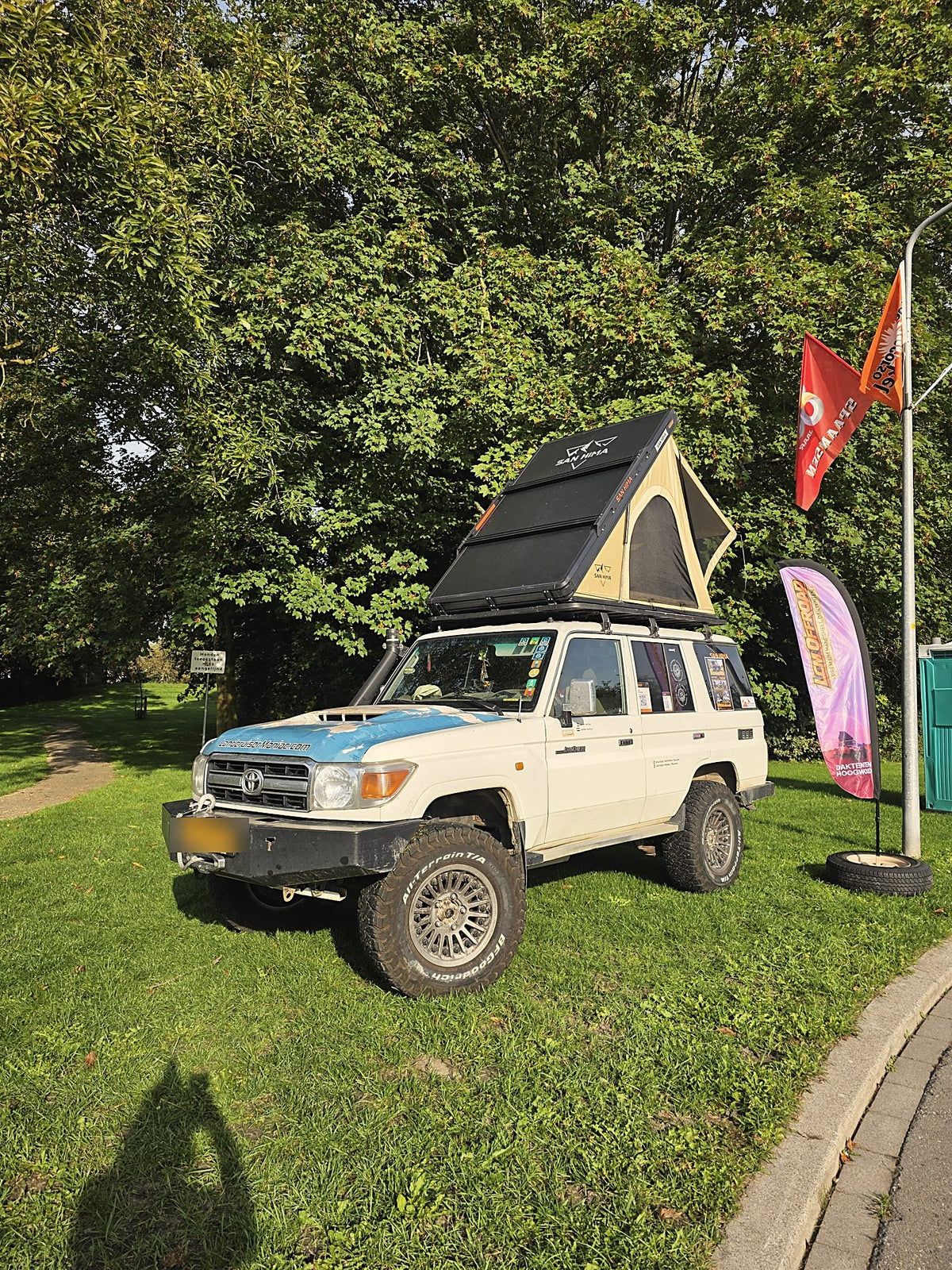 Land Cruiser with the khaki LCM hardshell rooftop tent open and an LCM Offroad beach flag